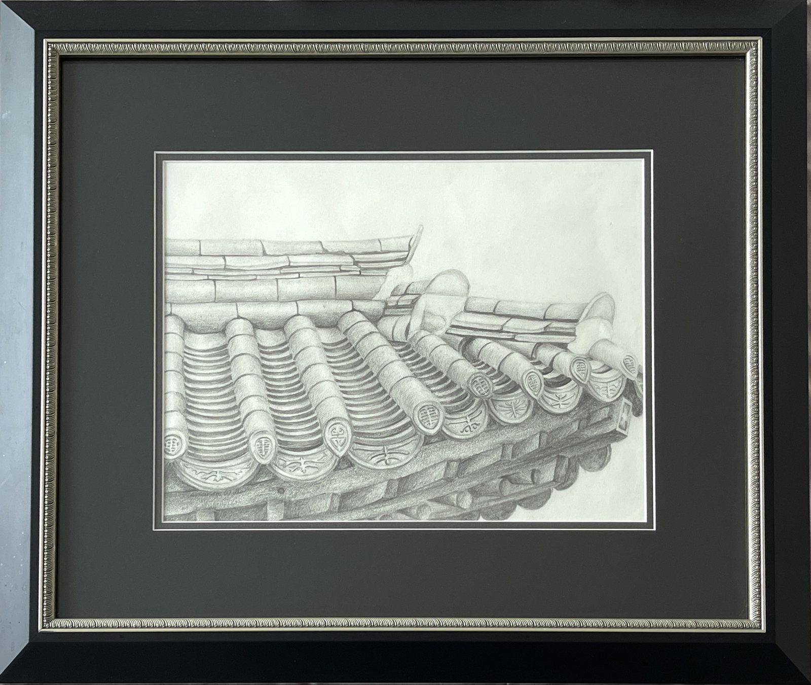 Graphite study of curved Korean roof tiles with decorative stamped end-caps, the arch over the gate to the house.